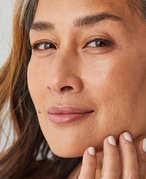 Picture of a mature model softly smiling and touching their chin