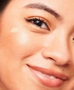 photo of person applying foundation and smiling