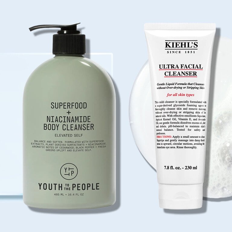 Bottle of Youth to the People and Bottle of Kiehl’s Ultra Facial Cleanser against a blue background with a soapy texture across it