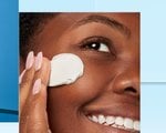 A woman rubbing a lotion into her face